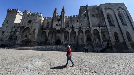 Une passante devant le Palais des papes d'Avignon, haut lieu du Festival international de théâtre d'Avignon, en 2019. (BORIS HORVAT / AFP)