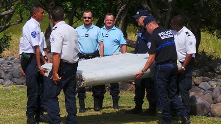 Des gendarmes et des policiers portent le d&eacute;bris d'avion retrouv&eacute; sur le littoral de La R&eacute;union, mercredi 29 juillet.&nbsp; (PRISCA BIGOT / ZINFOS 974 / REUTERS)