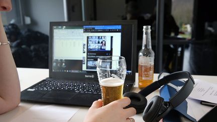 Une femme en télétravail boit une bière. (VANESSA MEYER / MAXPPP)