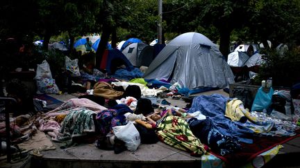 Ils dorment sur la place Victoria d'Athènes et près d'un graffiti sur le mur proclamant "solidarité avec les migrants".
 (Angelos Tzortzinis / AFP)