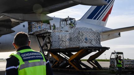 Des employés&nbsp;de l'aéroport Charles de Gaulle à Roissy déchargent des masques en provenance de Chine sur le tarmac, le 30 avril 2020. (BERTRAND GUAY / AFP)