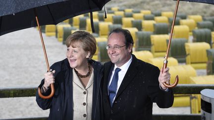 La chanceli&egrave;re allemande Angela Merkel (G) et le pr&eacute;sident fran&ccedil;ais Fran&ccedil;ois Hollande s'abritent de la pluie lors d'une promenade &agrave; Binz (Allemagne), le 9 mai 2014. (ODD ANDERSEN / AFP)