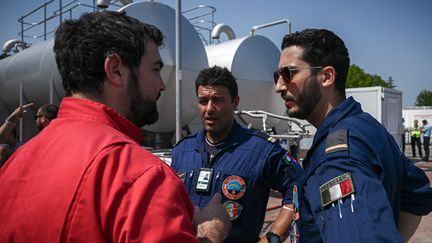 Des pilotes de Canadair italiens (en bleu) échangent avec un pompier français sur la base militaire de Mérignac où sont stationnés les avions qui luttent contre les incendies en Gironde. (PHILIPPE LOPEZ / AFP)