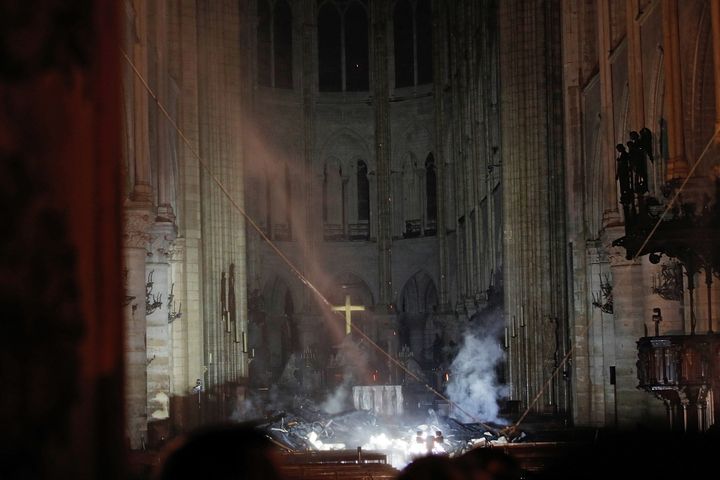 De la fumée s'élève devant la croix d'autel de la cathédrale Notre-Dame de Paris, le 15 avril 2019, après l'incendie qui a ravagé l'édifice. (PHILIPPE WOJAZER / AFP)