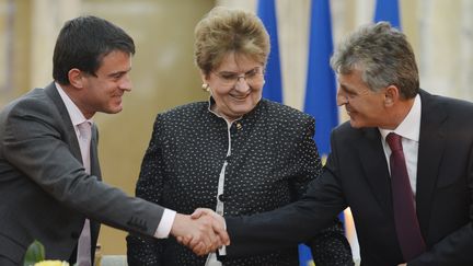 Manuel Valls et le ministre roumain de l'Int&eacute;rieur Mircea Dusa se serrent la main sous le regard de la ministre du travail Mariana Campeanu, le 12 septembre 2012 &agrave; Bucarest. (DANIEL MIHAILESCU / AFP)