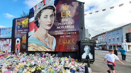 Les bouquets de fleurs s'accumulent devant cette fresque en hommage à la reine Elizabeth II, à Belfast. (AGATHE MAHUET / RADIO FRANCE)