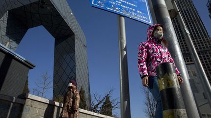 des pietons marchent aux abords du siège de la télévision centrale chinoise, située dans le nouveau quartier d'affaires à l'est de la capitale. L'alerte rouge y avait été déclenchée six jours plus tôt comme dans 27 autres grandes villes du nord de la Chine.
Ce niveau maximal d'alerte à la polution atmosphérique permet, en principe, d'instaurer des mesures d'urgence, comme la fermeture d'écoles, l'arrêt ou la réduction de la production des usines, la circulation alternée, le renfort de bus électriques ou encore l'interruption des chantiers. Des centaines de vols ont également été annulés en raison du manque de visibilité. Mais dans le Hebei (Nord), la province industrielle qui entoure Pékin, plusieurs aciéries et cimenteries n'ont pas respecté les interdictions. Dans la capitale, sur la seule journée du 20 décembre, plus de 80.000 véhicules ont enfreint la circulation alternée. Pékin avait décrété sa première alerte rouge en décembre 2015, en pleine conférence de Paris sur le réchauffement climatique.  (AP Photo / Sipa  Ng Han Guan)