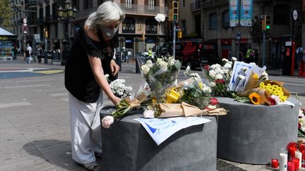 Une femme dépose des fleurs sur les Ramblas à Barcelone (Espagne), le 17 août 2020, trois ans après les attentats jihadistes&nbsp;qui ont tué 16 personnes.&nbsp; (JOSEP LAGO / AFP)