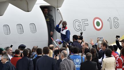 Un demandeur d'asile&nbsp;&eacute;rythr&eacute;en salue la foule venue assister au premier transfert de r&eacute;fugi&eacute;s au sein de l'UE, depuis Rome (Italie), le 9 octobre 2015. (ANDREAS SOLARO / AFP)