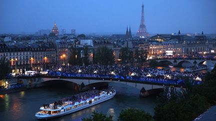 Le "Paquebot" transporte les sportifs de la délégation française sous le regard des spectateurs, avec la tour Eiffel à l'horizon. (RICHARD HEATHCOTE / AFP)