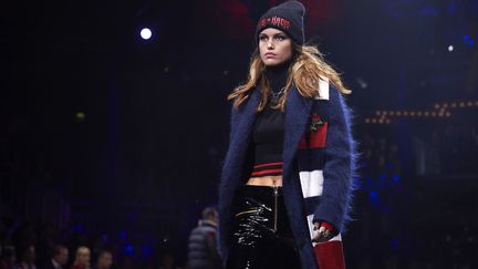 Tommy Hilfiger a clôturé la Fashion Week avec un show pharaonique ambiance concert de rock pour célébrer son premier défilé hors des Etats-Unis. Déterminé à rendre hommage à ce Londres des seventies qui l'a inspiré dans sa jeunesse, l'Américain de 66 ans s'est installé à la "Roundhouse", salle mythique de concerts. Des images retransmises en direct sur un écran géant circulaire, une sono explosive et 64 modèles pour un "show à l'américaine". Mannequin star d'une collection qu'elle a contribué à créer, Gigi Hadid lance le défilé vêtue d'un short en jean déchiré et d'un pull court à col montant, dans des tons noirs et rouges, un long manteau en laine mohair sur le dos. "Gigi est très impliquée dans la conception de la collection" a expliqué Tommy Hilfiger. "Beaucoup d'idées sont venues de son style". La marque profite de l'influence sur les réseaux sociaux de la top model, suivie par 36 millions de personnes sur Instagram. Dans la famille Hadid, il y aussi Bella, la soeur, qui défile avec une robe noire à capuche casual ornée d'un graphisme à sequins sur la poitrine. Qui dit rock, dit cuir : blousons biker coupe longue à poignets zippés et imprimés félins, shorts en cuir à garnitures dorées. Royaume-Uni oblige, le couturier puise dans le patrimoine écossais : mini-jupe rouge à franges à motif tartan inspirée des kilts traditionnels avec une touche de streetwear en l'agrémentant d'un sweat-shirt avec un appliqué aigle. C'était la 3e présentation du concept "TOMMYNOW", défilé itinérant s'inspirant des tournées des groupes de musique et qui a déjà posé ses valises à New York en 2016 et en Californie en février 2017. Ici, le vestiaire est mis en vente immédiatement, en "see now, buy now" ("aussitôt vu, aussitôt acheté"), tendance qui émerge depuis quelques saisons et qui devrait s'installer durablement, dixit Tommy Hilfiger. "Les jeunes, lorsqu'ils voient quelque chose sur les podiums ou quelque chose qui a l'air cool, veulent le porter le lendemain. Pas attendre six mois", a souligné le styliste, convaincu que le secteur doit saisir les opportunités qu'offrent les nouvelles technologies et les réseaux sociaux. "C'est une chance de vivre à l'ère numérique et ce serait une erreur que d'essayer d'aller à rebours".
 (NIKLAS HALLE&#039;N / AFP)