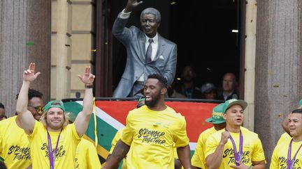 L'équipe de rugby sud-africaine, devant un statut de Nelson Mandela à Cap Town, le 11 novembre 2019, après leur victoire à la coupe du monde. (NIC BOTHMA / EPA)