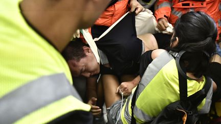 Un&nbsp;homme pris en charge par les secours à l'aéroport de Hong Kong après avoir été&nbsp;frappé par des manifestants, mercredi 14 août.&nbsp; (ANTHONY WALLACE / AFP)