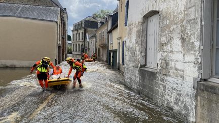 Des secouristes dans une rue inondée de Craon (Mayenne), le 20 juin 2024. (LAETITIA DREVET / AFP)