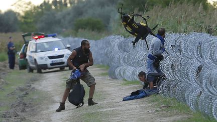 &nbsp; (Des policiers hongrois regardent des migrants syriens franchir la clôture en barbelés entre la Serbie et la Hongrie. © REUTERS/Laszlo Balogh)