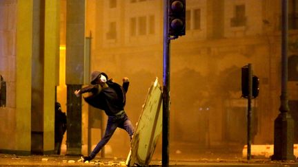 Un manifestant libanais jette des pierres sur la police anti-émeute lors d'affrontements près du Parlement dans le centre de Beyrouth le 19 janvier 2020. (PATRICK BAZ / AFP)