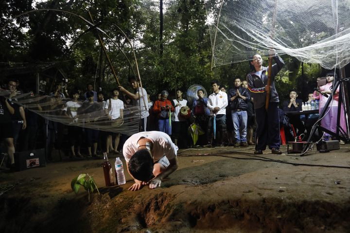 Des proches des enfants disparus dans la grotte de Tham Luang (Thaïlande) prient pour leur retour à l'entrée de la cavité, le 26 juin 2018. (KRIT PHROMSAKLA NA SAKOLNAKORN / AFP)