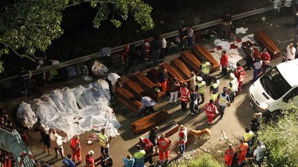 Des cadavres sont align&eacute;s &agrave; c&ocirc;t&eacute; de cercueils pr&egrave;s de l'endroit o&ugrave; un bus s'est &eacute;cras&eacute; en contrebas d'un pont &agrave; Avellino (Italie), le 29 juillet 2013. (CIRCO LUCA / REUTERS)