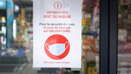 Une affichette rappelle l'obligation du port du masque de protection sanitaire, sur la vitrine d'un magasin à Toulouse, le 15 octobre 2020. (ADRIEN NOWAK / HANS LUCAS)