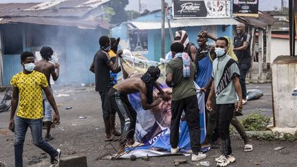 Des manifestants dégradent une affiche de campagne du président sortant Azali Assoumani, le 17 janvier 2024, à Moroni (Comores). (OLYMPIA DE MAISMONT / AFP)