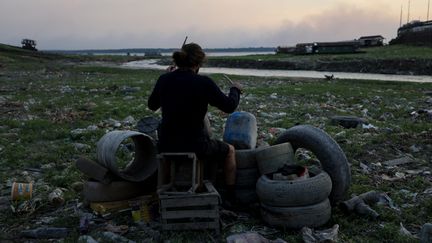 Le musicien Leonardo Pimente s'est confectionné une batterie avec les objets mis à jour par la sécheresse de la rivière, à Igarapé do Educando, sur le Rio Negro, près de Manaus, au Brésil, le 4 octobre 2023. (MICHAEL DANTAS / AFP)