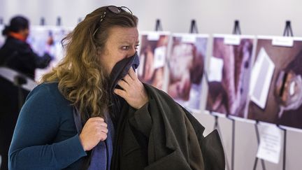 Une femme a du mal &agrave; retenir ses larmes devant une exposition organis&eacute;e &agrave; New York (Etats-Unis) et pr&eacute;sentant des photos de corps de victimes du r&eacute;gime syrien, prises&nbsp;par C&eacute;sar, un militaire qui a fui la Syrie en 2014 avec des milliers de clich&eacute;s. (LUCAS JACKSON / REUTERS)