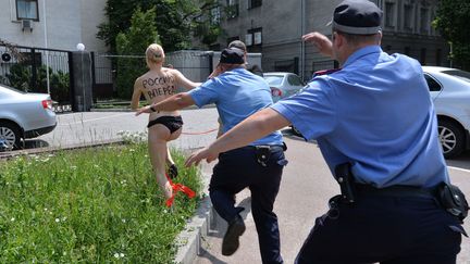 Des policiers courent apr&egrave;s une militante des Femen apr&egrave;s qu'elle s'est &eacute;cri&eacute;e "Vladimir, je t'aime" devant l'ambassade de Russie &agrave; Kiev (Ukraine), le 7 juin 2013. (SERGEI SUPINSKY / AFP)