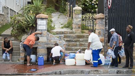 Des habitants remplissent des bidons d'eau, le 19 janvier 2018, à Saint James, une banlieue du Cap (Afrique du Sud). (RODGER BOSCH / AFP)