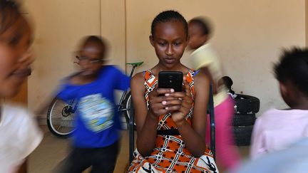 Imelda Mumbi, 13 ans, tient son smartphone alors qu'elle étudie en ligne à l'aide d'une application, à Nairobi, le 8 novembre 2018. (TONY KARUMBA / AFP)