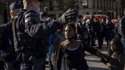 Un policier en train d'évacuer une migrante sur la place de l'hôtel de Ville à Paris, le 28 octobre 2021. (JULIEN DE ROSA / AFP)