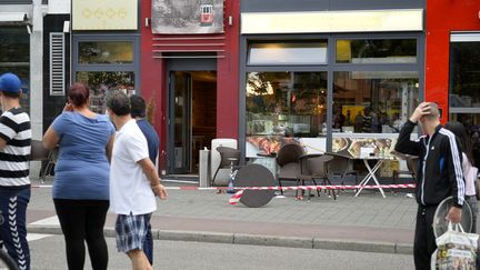 Des passants devant le restaurant où un homme a tué une femme à la machette, le 24 juillet 2016 à Reutlingen (Allemagne). (THOMAS KIENZLE / AFP)