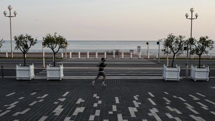 Un homme fait son jogging devant la Promenade des anglais dans la ville de Nice, le 3 avril 2020. (VALERY HACHE / AFP)