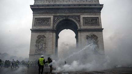 Des "gilets jaunes" font face aux forces de l'ordre devant l'Arc de Triomphe lors du troisième samedi de mobilisation du mouvement, le 1er décembre 2018. (ABDULMONAM EASSA / AFP)