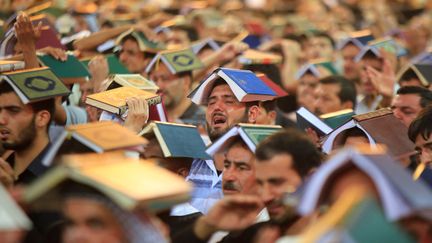 Des chiites pleurent l'anniversaire de la mort de l'imam Ali avec un Coran plac&eacute; sur la t&ecirc;te &agrave; Najaf (Irak), le 30 juillet 2013. (REUTERS)