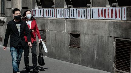 Un couple se promène en portant un masque devant l'hôpital Lariboisière, à Paris, le 12 mai 2020. (JOEL SAGET / AFP)