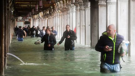 Des touristes sous une arche inondée à Venise en Italie, le 29 octobre 2018. (MIGUEL MEDINA / AFP)