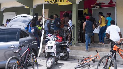 Des personnes se servent dans une boutique sur l'île de&nbsp;Saint-Martin après le passage de l'ouragan Irma, jeudi 7 septembre 2017. (LIONEL CHAMOISEAU / AFP)