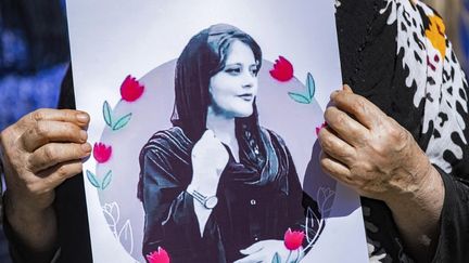 Une femme brandit un portrait de Mahsa Amini, une Kurde iranienne de 22 ans morte trois jours après son arrestation par la police des mœurs en Iran, lors d'une manifestation à Hasakeh (Syrie), le 25 septembre 2022. (DELIL SOULEIMAN / AFP)