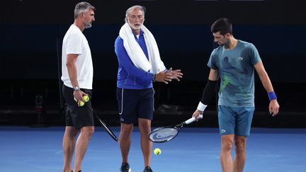 Le Serbe Novak Djokovic discute avec ses entraîneurs lors d'une séance d'entraînement à l'Open d'Australie, à Melbourne, le 13 janvier 2024. (DAVID GRAY / AFP)