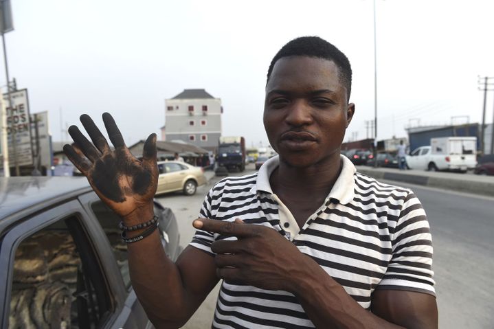 Un homme essuie sa voiture avec sa main pour montrer combien la suie en a recouvert le capot, dans la ville de Port Harcourt, le 14 février 2017. La suie est tombée du ciel provocant la colère des résidents qui affirment que rien n'est fait pour protéger leur santé. (PIUS UTOMI EKPEI/AFP)