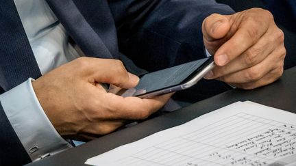 Un homme postule avec son smartphone. (MICHAEL KAPPELER / DPA)