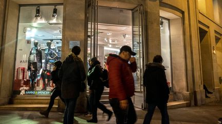 Des personnes sur les Champs Élysées devant une boutique ouverte la nuit.&nbsp; (MAXPPP)