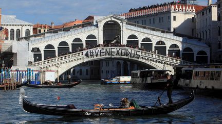 Une banderole dénonçant l'exode forcé des Vénitiens face au tourisme de masse, déployée sur le pont du Rialto, le 12 novembre 2016, à Venise (Italie). (MANUEL SILVESTRI / REUTERS)