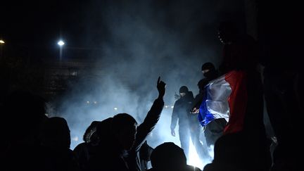 Des supporters de foot célèbrent la victoire de l'équipe de France contre le Maroc lors de la demi-finale du mondial au Qatar, à Paris, le 15 décembre 2022. (JULIEN DE ROSA / AFP)