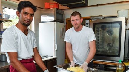 Adil Muhammad, un Pakistanais, travaille avec le chef Sebastian Knuth dans les cuisines du Strandhotel Buckow en Allemagne. Ce patron dit avoir de grandes difficultés à recruter du personnel et s'est donc tourné vers l'embauche de réfugiés. (PATRICK PLEUL / ZB / DPA / AFP)