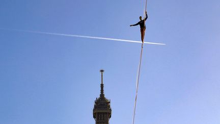 Nathan Paulin lors de sa traversée sur une sangle tendue au-dessus du vide entre la tour Eiffel et le Trocadéro, le 9 décembre 2017, dans le cadre du Téléthon. (JACQUES DEMARTHON / AFP)