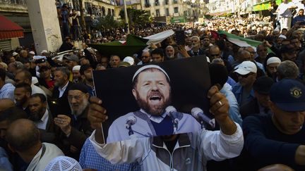 Contestation du Hirak pour l'élection présidentielle en Algérie. Un manifestant brandit une photo d'Abassi Madani, l'ancien leader du Front Islamique&nbsp;du Salut (FIS) mort en exil au Qatar. Photo prise le 27 avril 2019.&nbsp;&nbsp; (RYAD KRAMDI / AFP)