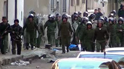 Des forces de s&eacute;curit&eacute; syriennes avancent sur les protestants &agrave; Homs, en Syrie le 1er janvier 2012. (STR / AFPTV / AFP)