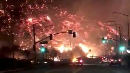 Au matin du 6 décembre 2017, les automobilistes qui empruntent tous les jours l'autoroute 405, au cœur de Los Angeles, ont eu la stupeur de rouler&nbsp;à quelques mètres de collines en flammes, comme le montre cette photo prise par une internaute. Elle a finalement en partie été fermée. (SOCIAL MEDIA / REUTERS)