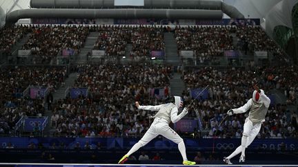 L'Américain Alexander Massialas (à gauche) affronte le Français Enzo Lefort dans le combat pour la médaille de bronze par équipes de fleuret masculin entre les États-Unis et la France lors des Jeux Olympiques de Paris 2024 au Grand Palais à Paris, le 4 août 2024. L'arbitrage de cette discipline s'effectue entièrement en français. (FABRICE COFFRINI / AFP)